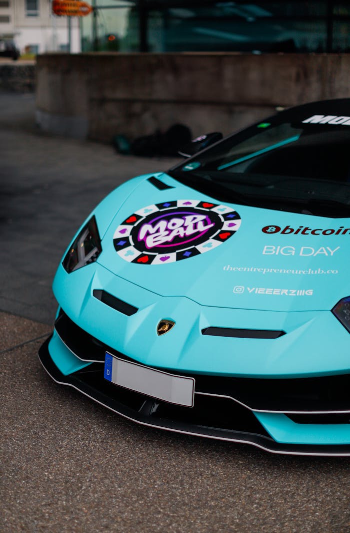 about-01 Close-up of a customized turquoise sports car with branding decals in urban setting.