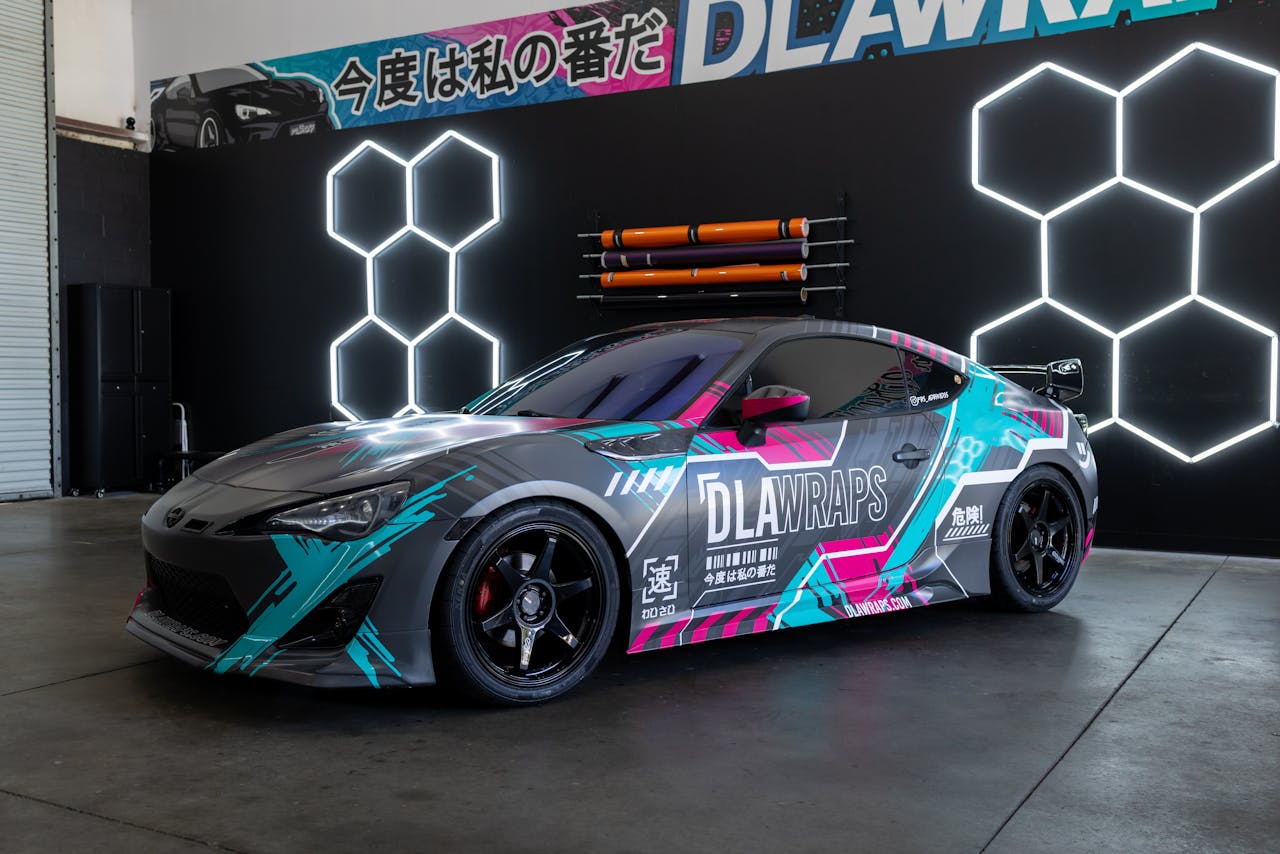 hero-img-02 Dynamic photo of a sleek sports car with colorful custom vinyl wrap by DLA Wraps in a shop setting.