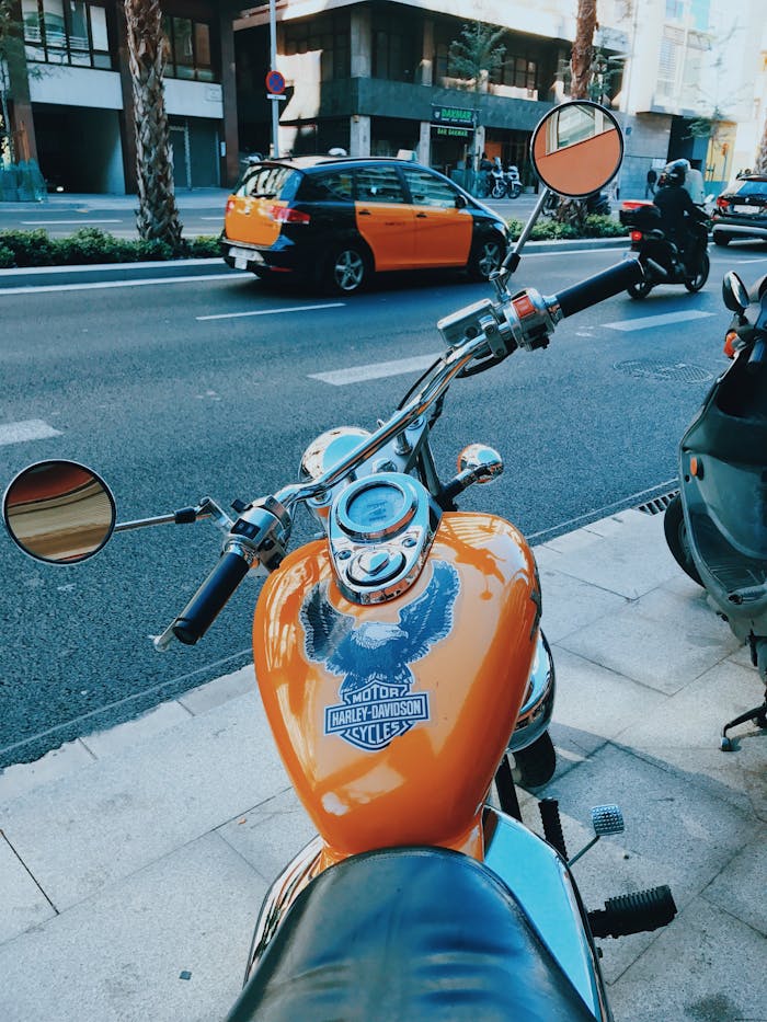 gallery-3 Close-up of a Harley Davidson motorcycle parked on a street in Barcelona, Spain, with urban surroundings.